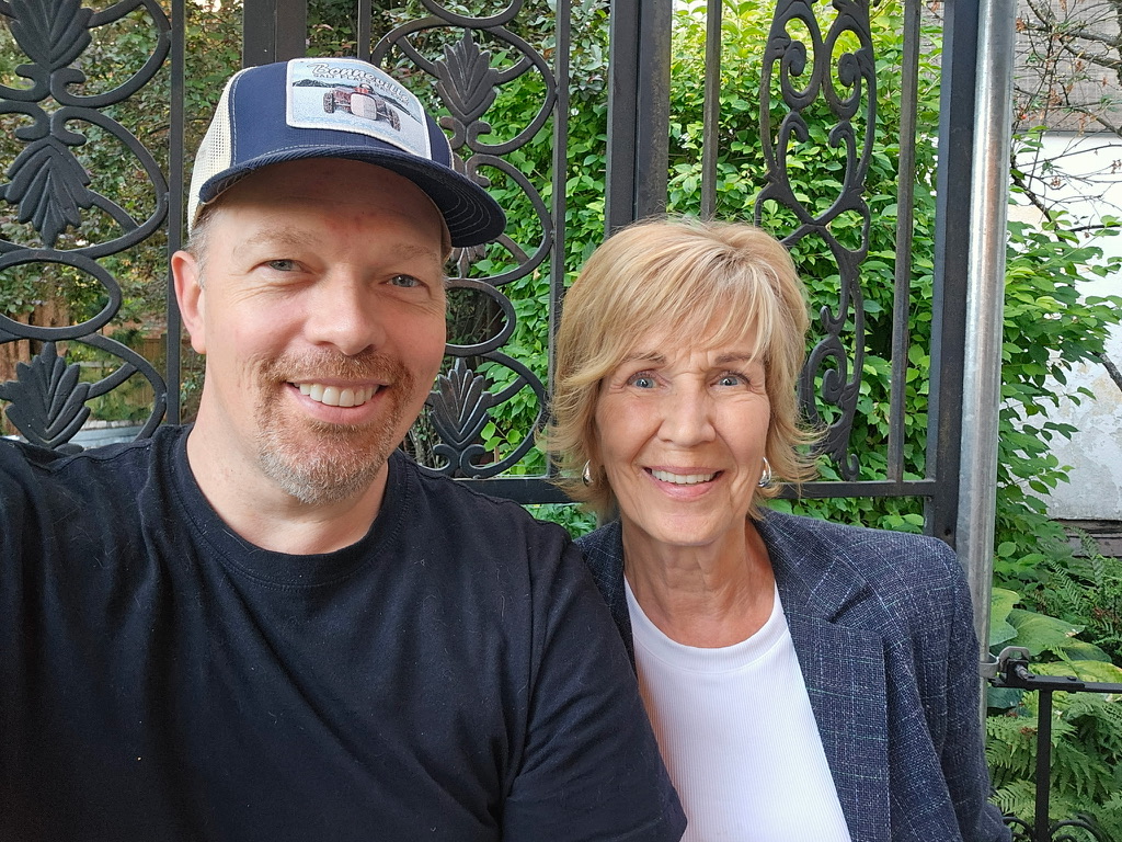 Two members grinning in front of a garden gate