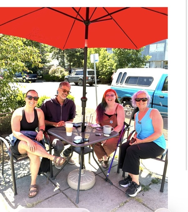 Four members sharing a table under a red umbrella