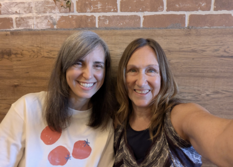 Two members laughing together against a brick wall